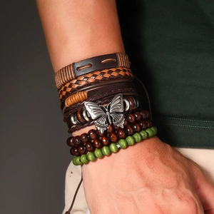 Détail de bracelets bohèmes avec cuir tressé, perles en bois et pendentif papillon argenté