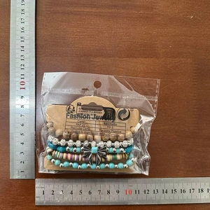Detail view of 5-piece beaded bracelet set with bow charms on a wooden surface