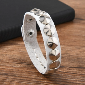 Détail d'un bracelet en cuir PU blanc avec des clous en métal argenté et bouton pression