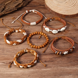 Détail de 6 bracelets bohèmes perlés avec coquillages et étoiles sur fond en bois