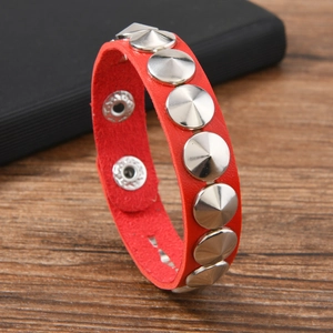 Détail d'un bracelet en cuir punk rouge avec rivets coniques et boutons-pression