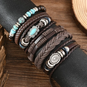 Details von mehrlagigen Boho-Armbändern mit Türkisperlen und Ledergeflecht auf Holz