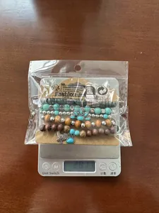Detailed view of bohemian wood bead bracelet set with hand charm on weighing scale
