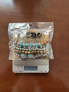Détail d'un bracelet bohème multicouche sur balance pesant 37,9 g avec breloques cactus