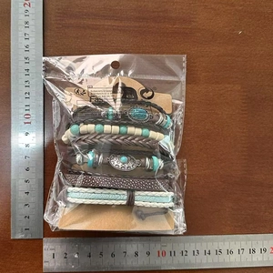 Dettaglio di bracciali multistrato in pelle con perline turchesi e ciondoli retrò