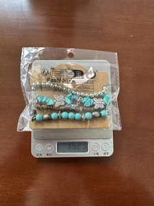 Detail view of bohemian turquoise and wood bead bracelets with butterfly charm on a scale