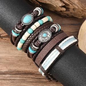Set bracciali multistrato in pelle e pietre turchesi su sfondo in legno vintage