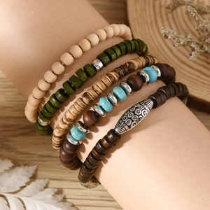 Close-up of bohemian layered turquoise and wood bead bracelet set with silver metal charms