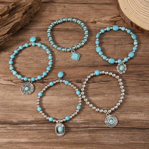 Bohemian five-piece turquoise bead bracelet set with silver sun charms on wood