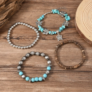 Bohemian turquoise bead and coconut shell bracelets with a butterfly charm on wood surface