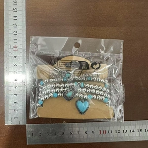 Détail d'un ensemble de bracelets bohèmes en perles turquoise avec breloques cœur