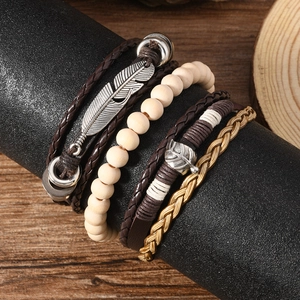 Gros plan sur des bracelets multicouches en cuir avec pendentifs plume et feuille