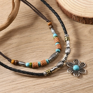 Detailed view of bohemian layered necklace with turquoise beads and silver flower pendant