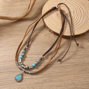Bohemian multi-layer leather necklace with turquoise teardrop pendant on wooden background