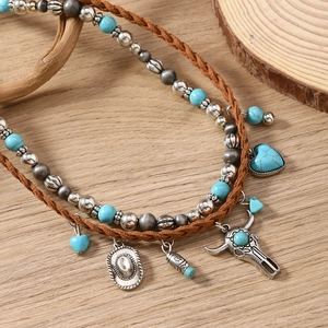 Detailed close-up of bohemian cow skull and heart turquoise pendants on a beaded necklace
