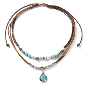 Detail of bohemian double-layer necklace with turquoise pendant and silver-etched tubes