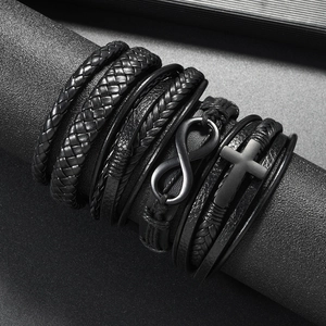 Men's multilayer black leather bracelet with infinity and cross charms on textured stand