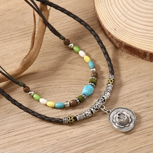 Detail of bohemian layered necklace featuring colorful beads and vintage cowboy hat pendant