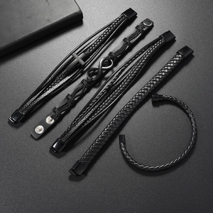 Macro shot of 5-piece men's black leather bracelets with infinity and cross metal charms