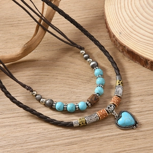 Detail of bohemian layered necklace with heart turquoise pendant and woven leather cord