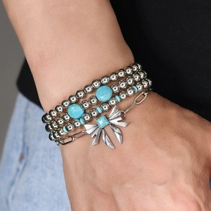 Detail of bohemian silver beaded bracelets with blue turquoise and a metal bow charm
