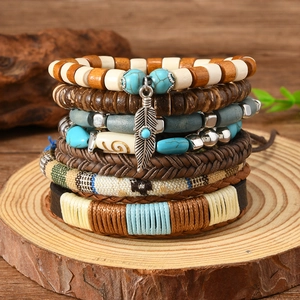 Detail of bohemian multilayered leather and turquoise bead bracelets with a metal feather charm