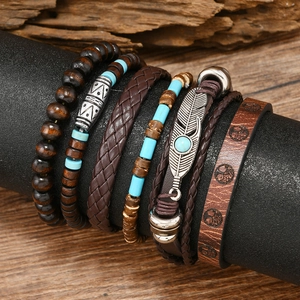 Détail de bracelets multicouches vintage en cuir avec breloques œil et plumes