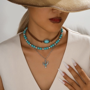 Detail van een bohemian gelaagde kettingset met turquoise kralen en een cactus-hanger