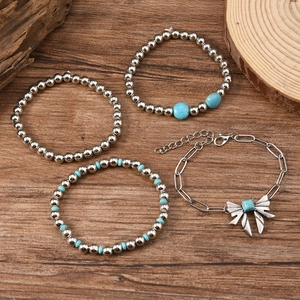 Detail of four-piece Bohemian stackable bracelet set with turquoise beads and bow charm