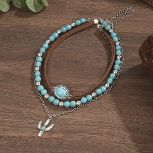 Detail van gelaagde turquoise ketting met boho cactusbedels op een donkere houten basis