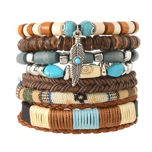 Detail of bohemian layered bracelets featuring turquoise beads, wood, and feather charms