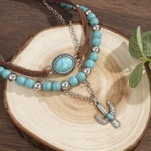 Detail van de bohemian turquoise kralenketting met zilveren cactus hanger op hout