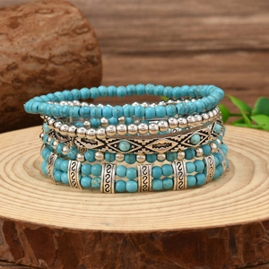 Bohemian multi-layer turquoise beaded bracelet set on a natural wood stump base