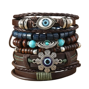 Detail view of retro braided leather bracelet set with blue evil eye and bull head charms
