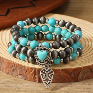 Detail of bohemian turquoise beads and vintage silver pendants on wood surface