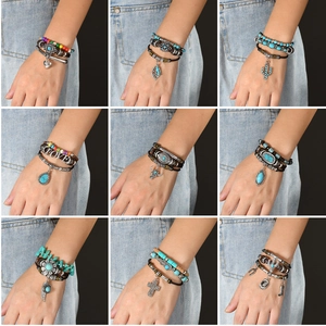 Detailed close-up of bohemian multilayer leather bracelets with turquoise and metal charms