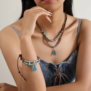 Detail of layered turquoise pendant necklace and bracelet set on denim outfit