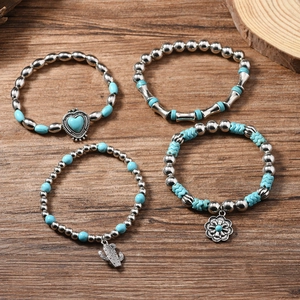Detail of four-piece Bohemian beaded bracelets with turquoise charms on dark wood