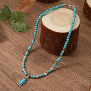 Bohemian turquoise beaded necklace with drop pendant on a rustic wood background