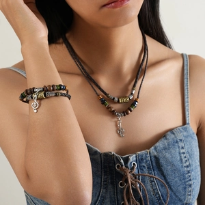 Close-up of retro ethnic wolf fang beads necklace and G-clef pendant with woven cord