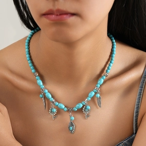 Collier bohème turquoise avec pendentifs feuilles et fleurs porté sur tenue denim