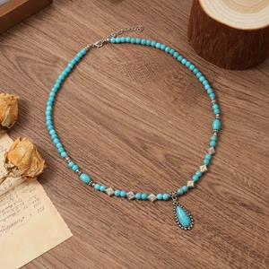Close-up of bohemian turquoise beaded necklace with drop pendant on vintage wood background