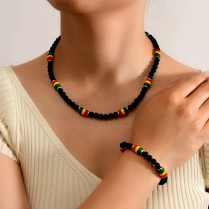 Close-up of bohemian matte black beaded necklace and bracelet set on model wearing beige