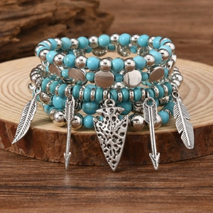 Detail of bohemian turquoise and wood bead bracelets with silver feather and arrow charms