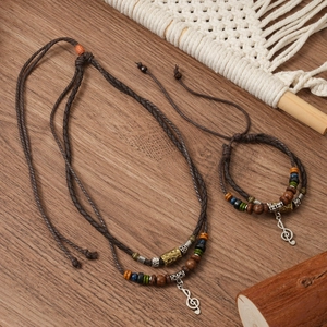 Close-up of ethnic double-layered woven necklace with wolf tooth and music note charms