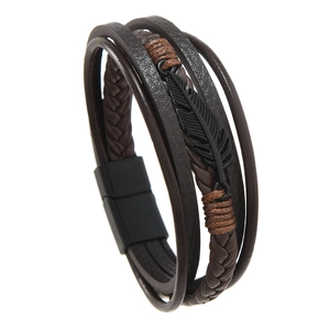 Macro view of multi-layer leather bracelet featuring a black metal feather and magnetic clasp