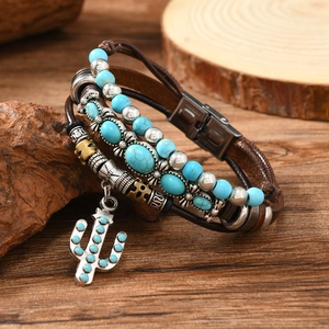 Detail of leather wrap bracelet featuring turquoise beads and a cactus pendant on wood