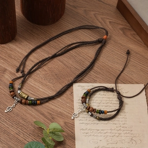 Close-up of bohemian woven necklace and bracelet set with musical note pendants on wood