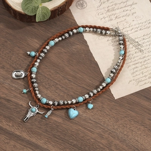 Detail van boho-halsketting met turquoise kralen, stierenschedel en cowboyhoed-hangers