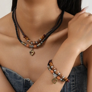 Detail of vintage layered woven necklace and bracelet set with heart pendant on a model